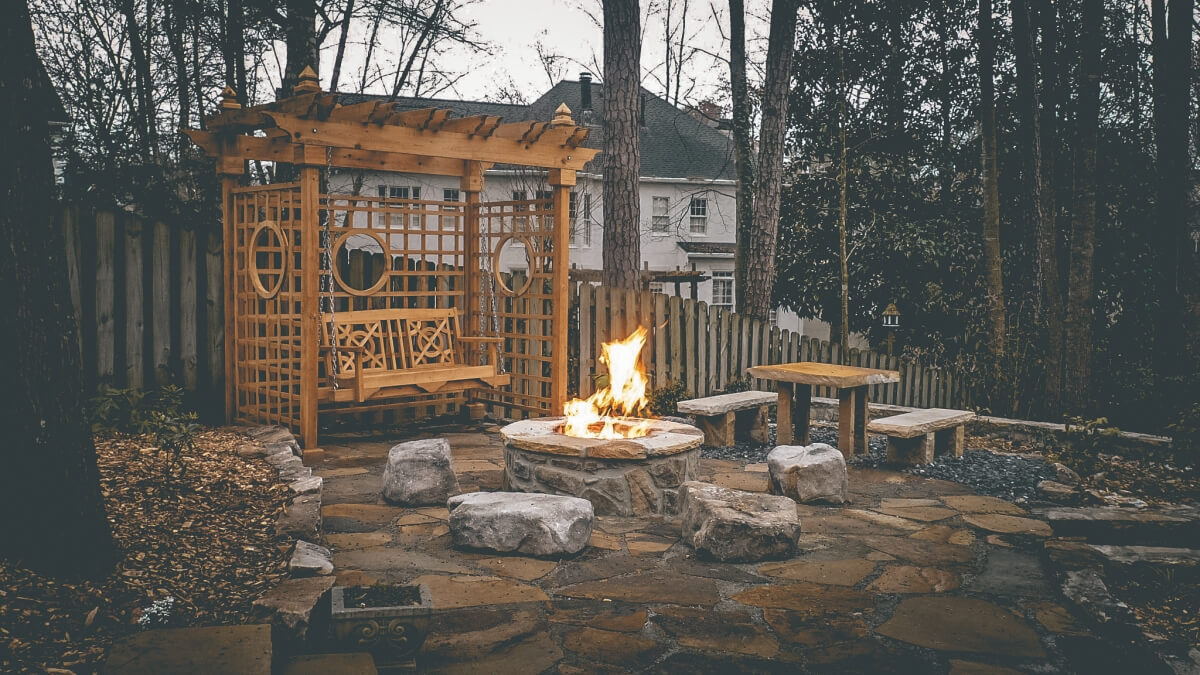 swing and pergola next to backyard fire pit in winter