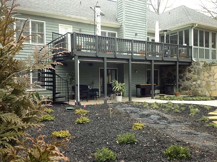backyard deck with spiral stair case leading down to backyard with mulch and softscaping