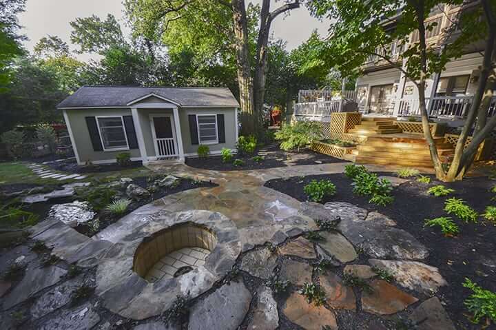 backyard guest house next to stone fire pit and wooden deck with designer outdoor landscaping