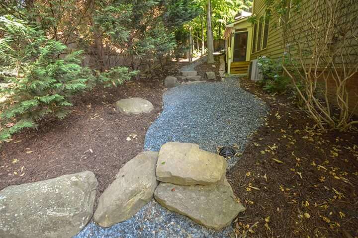 gravel and rock xeriscaping in backyard with fence and landscaping