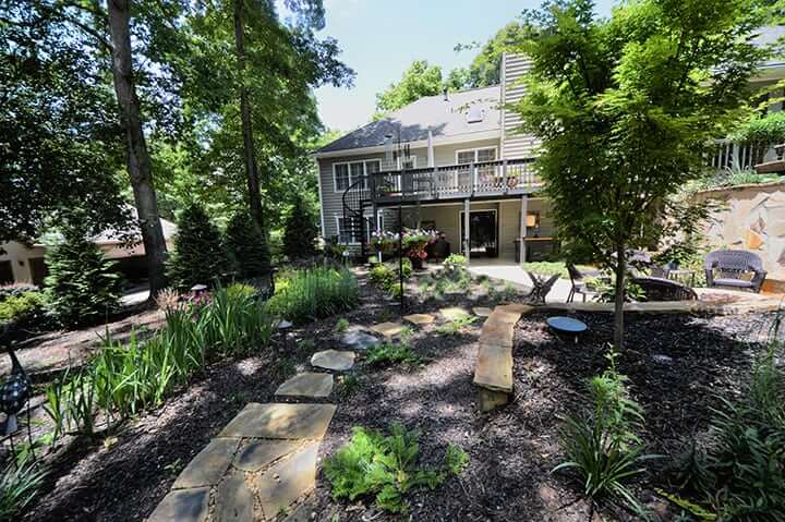 backyard with landscaping and softscaping for house with black back deck and outdoor living space