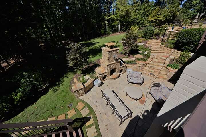 landscaped stone patio and outdoor living space with stone fire place and outdoor furniture