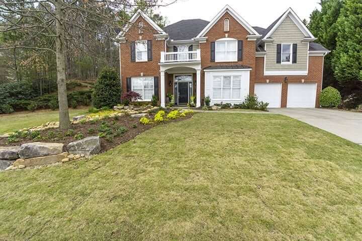 front yard of georgia brick home with green grass and landscaping design